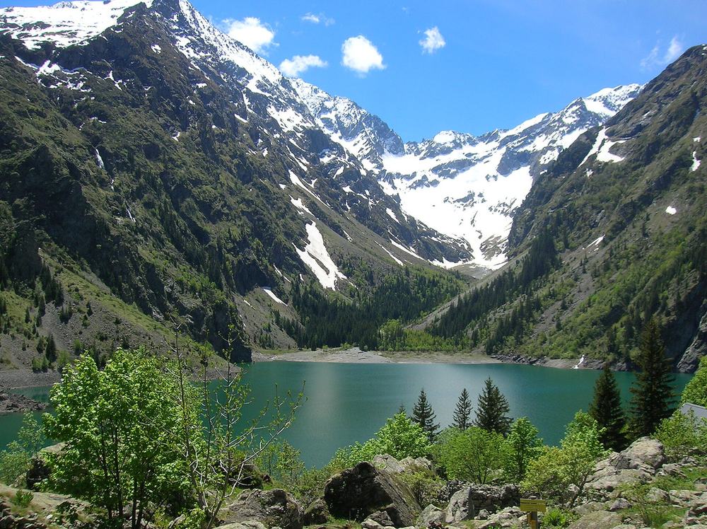 Le lac Lauvitel aux eaux vertes, encaissé entre les versants boisés et les sommets enneigés