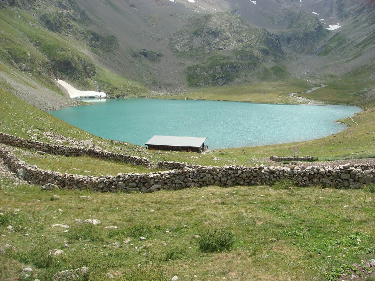 Le lac de la Muzelle et son refuge, en août, sous les pentes herbeuses