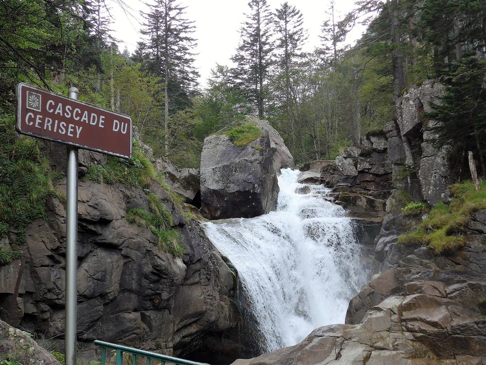 La cascade du Cerisey entre les rochers, avec son panneau
